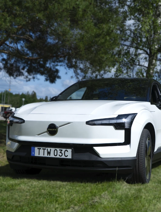 En vit Volvo EX30 som står parkerad i gräset.