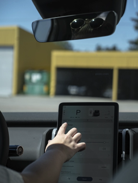 Volvo EX30s interiör. Bilden visar förarens hand som rör skärmen.